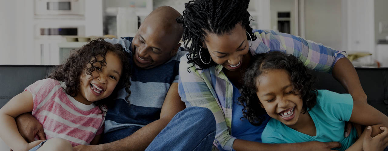 Playful family of four on sofa in living room