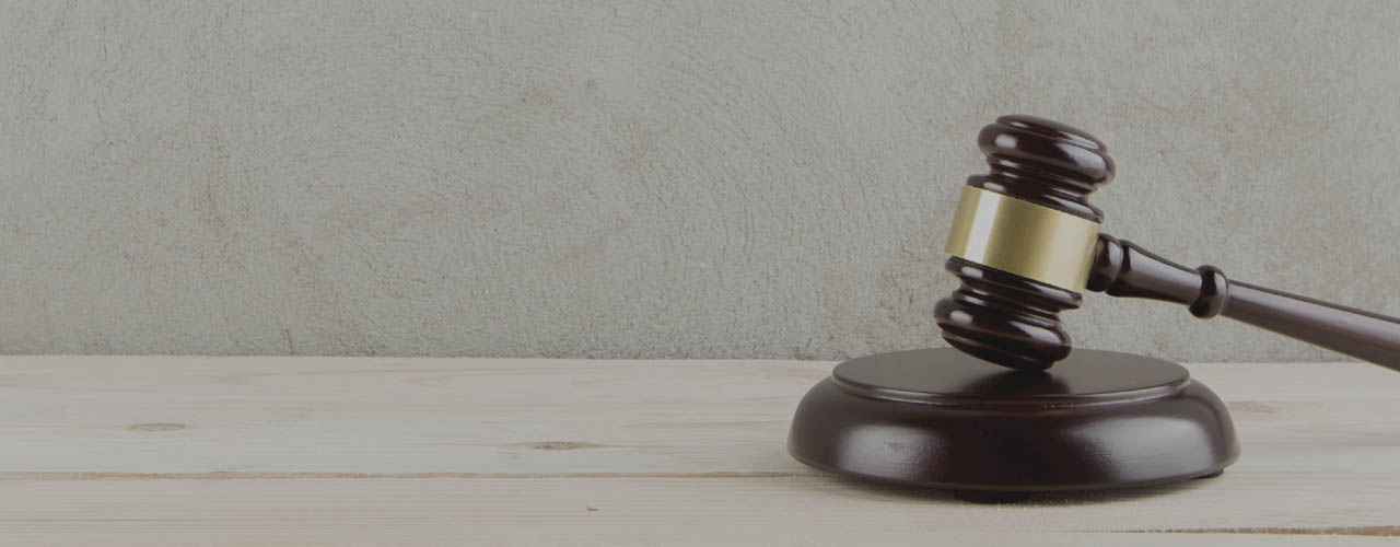brown gavel with a brass band on a grey background