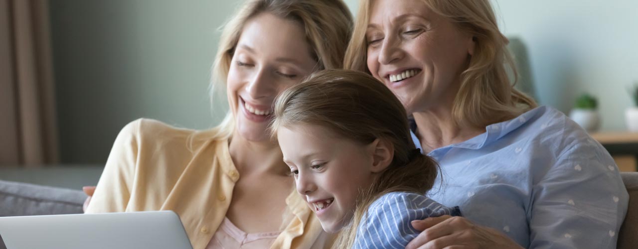 Little girl with mother and grandmother watch movie on laptop